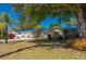 Single-story home with a blue roof and mature landscaping in a lush green setting at 28482 Coco Palm Dr, Punta Gorda, FL 33982