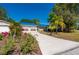 Charming home with a blue metal roof, front yard flowers, an extra-long concrete driveway and lush landscaping at 28482 Coco Palm Dr, Punta Gorda, FL 33982