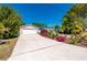 Landscaped front yard with colorful flowers, a long driveway and an attached two-car garage at 28482 Coco Palm Dr, Punta Gorda, FL 33982