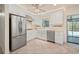 Bright kitchen features stainless steel appliances, tiled floor, white cabinetry, farmhouse sink, and access to the lanai at 28482 Coco Palm Dr, Punta Gorda, FL 33982