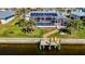 An aerial view shows a home near a canal with a screened pool, a dock, and solar panels at 529 Belvedere Ct, Punta Gorda, FL 33950