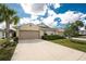 Inviting beige single story home featuring a wide driveway, lush landscaping, and two-car garage at 7393 West Lenox Cir, Punta Gorda, FL 33950