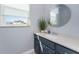 Bathroom vanity features a quartz countertop, navy blue cabinets and a modern round mirror at 1052 Eppinger Dr, Port Charlotte, FL 33953