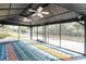 Interior view of the screened lanai featuring two ceiling fans and a colorful outdoor rug at 1052 Eppinger Dr, Port Charlotte, FL 33953