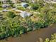 Aerial view of a private home surrounded by mature trees, a long driveway, and a waterfront view at 3896 Slayton Ave, North Port, FL 34286