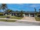 Home exterior featuring tropical landscaping, a well-manicured lawn, and a two-car garage at 125 Ott Cir, Port Charlotte, FL 33952