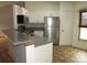 Well-lit kitchen with stainless steel refrigerator, breakfast bar, and tile flooring at 1247 Petronia St, North Port, FL 34286