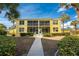 Two-story yellow building with screened patios and lush landscaping on a sunny day at 2000 Bal Harbor Blvd # 1-111, Punta Gorda, FL 33950