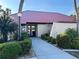 Community clubhouse featuring mature palms, lush landscaping, and an inviting entrance at 3006 Caring Way # 409, Port Charlotte, FL 33952