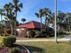 Community clubhouse featuring a unique roofline, mature palms, and lush landscaping at 3006 Caring Way # 409, Port Charlotte, FL 33952