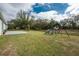 Expansive backyard with a swing set, mature trees, and a concrete patio at 3264 Garbett Ter, North Port, FL 34288