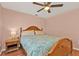 Comfortable bedroom featuring a ceiling fan, window, and a wooden bed frame with side table and lamp at 4175 Horseshoe Ave, North Port, FL 34286