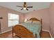 Cozy bedroom with a ceiling fan, window with blinds, and a wooden bed frame with a blue comforter at 4175 Horseshoe Ave, North Port, FL 34286
