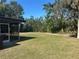 This home features a lush green backyard lawn, an outdoor screen enclosure, and a peaceful outdoor space at 432 Olivia Rd, Venice, FL 34293