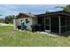 View of the home exterior with a screened patio, lush grass and utility equipment in the backyard at 432 Olivia Rd, Venice, FL 34293