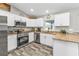 Modern kitchen with stainless appliances, granite countertops, white cabinets, and wood-style floors at 11338 Willmington Blvd, Port Charlotte, FL 33981