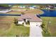 Aerial view of a single-story home with a paved driveway, lush lawn, and a waterfront location on a sunny day at 17122 Barcrest Ln, Punta Gorda, FL 33955