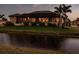 An evening exterior view from the water featuring the screened lanai and landscape lighting at 17122 Barcrest Ln, Punta Gorda, FL 33955