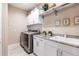 Functional laundry room with modern washer and dryer, granite counters, and ample storage space at 17122 Barcrest Ln, Punta Gorda, FL 33955