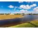 Scenic view of a tranquil body of water surrounded by lush green grass and single-Gathering homes under a blue sky at 17122 Barcrest Ln, Punta Gorda, FL 33955