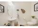 This half bathroom offers a pedestal sink, decorative mirror, framed art, and a white toilet against neutral walls at 20272 Lagente, Venice, FL 34293