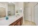 Bright bathroom features a dark wood vanity with white countertop, tiled floor and shower, and large mirror at 20272 Lagente, Venice, FL 34293