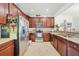 Well-lit kitchen with a stainless steel refrigerator, granite countertops, and wood cabinetry at 20272 Lagente, Venice, FL 34293