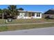 Charming home featuring a well-manicured front yard with a white bench and a yellow door at 21456 Holdern Ave, Port Charlotte, FL 33952