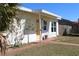 Charming home featuring a well-manicured front yard with a white bench and a yellow door at 21456 Holdern Ave, Port Charlotte, FL 33952