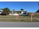 Charming single-story home with well-maintained lawn, palm trees, and a bright yellow front door at 21456 Holdern Ave, Port Charlotte, FL 33952