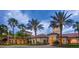 Beautiful clubhouse exterior with lush landscaping, mature palm trees, and ample parking space at 2478 Brassica Dr, North Port, FL 34289