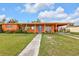 Charming one-story home featuring a bright orange exterior, blue door and lush green lawn at 520 Sharon Cir, Port Charlotte, FL 33952