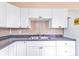 Updated kitchen with white cabinets, stainless steel sink, and tile backsplash at 520 Sharon Cir, Port Charlotte, FL 33952