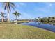 Backyard features a serene lake with lush greenery, palm trees, and a private dock at 9428 Bandera Ln, Port Charlotte, FL 33981