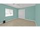 Inviting turquoise bedroom offers a serene atmosphere with light wood floors and ample natural light from a bright window at 9428 Bandera Ln, Port Charlotte, FL 33981