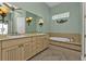 Bright bathroom featuring a double vanity sink, a standalone soaking tub and a light green accent wall at 960 Messina Dr, Punta Gorda, FL 33950