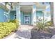 Front entrance of a beautiful light blue home with brick walkway and mature landscaping at 960 Messina Dr, Punta Gorda, FL 33950