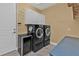 Laundry room with sleek black washer and dryer, wine cooler, and overhead cabinet for storage at 960 Messina Dr, Punta Gorda, FL 33950