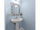 Powder room featuring a pedestal sink, decorative mirror, and blue walls at 960 Messina Dr, Punta Gorda, FL 33950