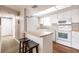 Bright kitchen featuring white appliances, cabinets, breakfast bar, and cozy stools with wood-look flooring at 1080 Bal Harbor Blvd # 4D, Punta Gorda, FL 33950