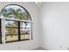 Bright bedroom featuring a large arched window with palm tree views and neutral walls at 1105 Rum Cay Ct, Punta Gorda, FL 33950