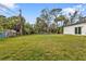 Expansive backyard featuring green grass and privacy with natural foliage and a white exterior with sliding glass doors at 1117 Vernon Ave, Port Charlotte, FL 33948