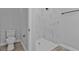 A modern bathroom offers a walk-in tiled shower, toilet, wood-look floors, and neutral grey walls at 1117 Vernon Ave, Port Charlotte, FL 33948