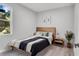 Cozy bedroom with light wood floors, bed with stylish comforter and accent pillows, and a bright window at 1117 Vernon Ave, Port Charlotte, FL 33948
