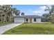 Charming single-story home with a well-maintained lawn, attached garage, and a bright yellow front door at 1117 Vernon Ave, Port Charlotte, FL 33948