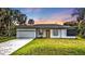 Charming single-story home with a yellow door, a well-manicured lawn, and a spacious driveway at 1117 Vernon Ave, Port Charlotte, FL 33948