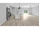 Open concept living room area with kitchen in the background, sliding glass door and neutral walls and floors at 1117 Vernon Ave, Port Charlotte, FL 33948