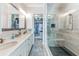 Elegant bathroom featuring double vanity, glass shower, and walk-in closet with custom shelving and clothing storage at 11723 1St E St, Treasure Island, FL 33706