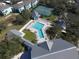 Aerial view of a community pool, tennis courts, clubhouse, and ample seating, surrounded by lush landscaping at 1286 Green Oak Trl, Port Charlotte, FL 33948