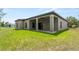 Exterior view of home with covered patio and spacious backyard with green grass at 1790 New London St, North Port, FL 34288